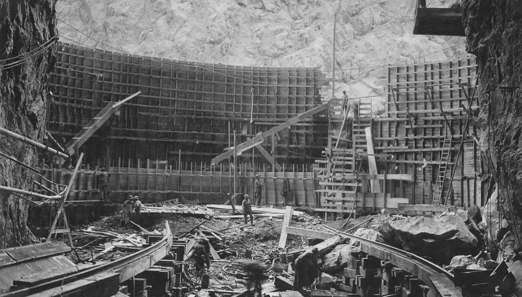 Construction site inside a rock cavern with timber shoring, scaffolding, and several workers