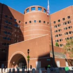 Large red brick courthouse with a rounded central tower and American flag on a tall pole in front.
